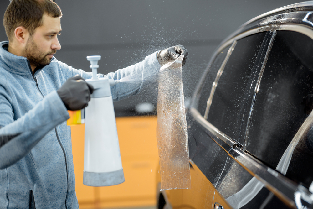 Technician applying protective coating to the surface of a car to enhance durability and corrosion resistance